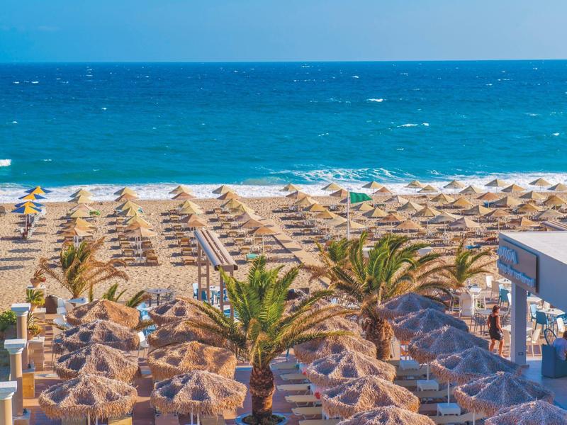 Playa con muchas sombrillas y vista al mar azul en destino vacacional.