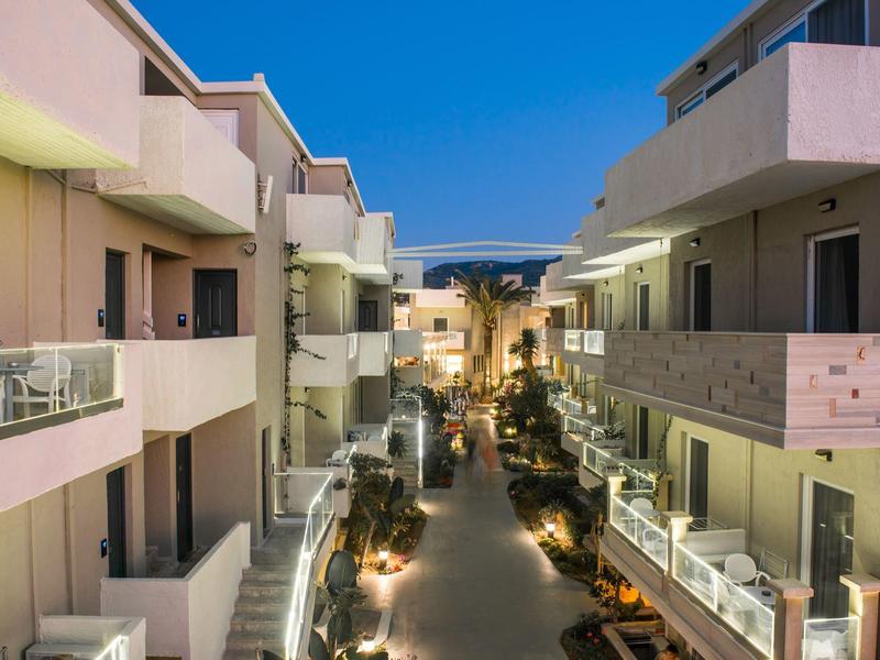 Vista nocturna de un hotel iluminado con balcones y cielo despejado.