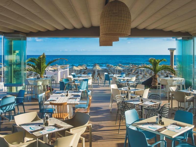 Restaurante abierto con decoración moderna y vista al mar en un día soleado