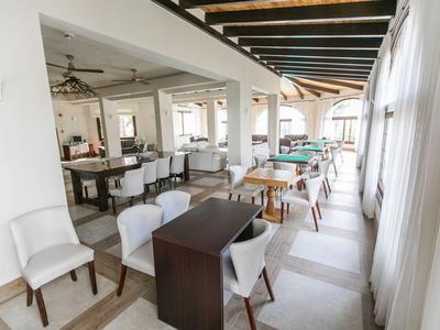 Bright modern restaurant with white chairs, wooden tables, and large windows.