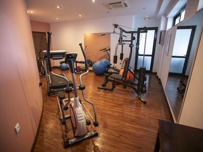 A small gym room with various exercise machines and wooden flooring.