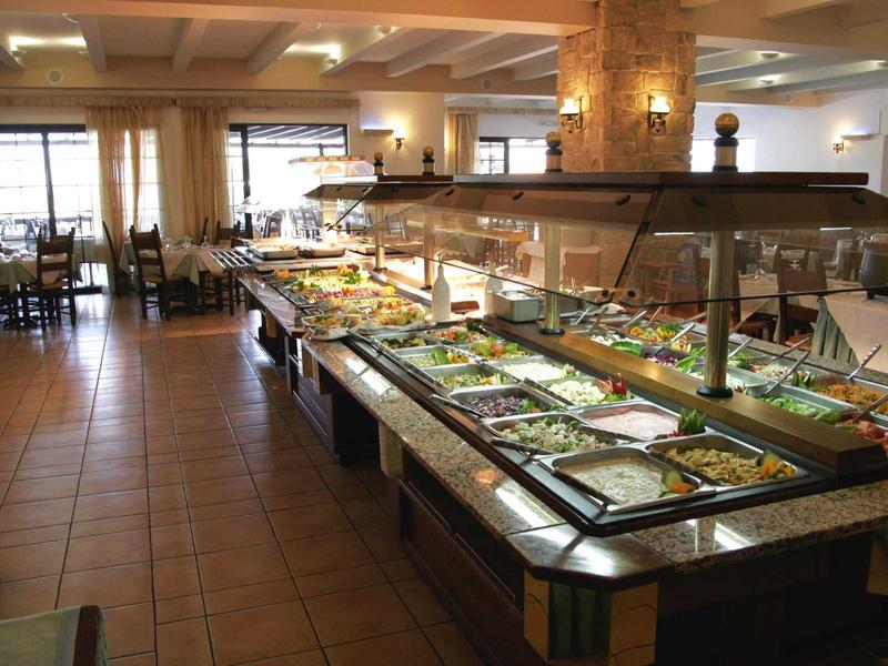 Buffet con varie insalate e piatti in un ristorante con pavimento piastrellato e molta luce naturale.