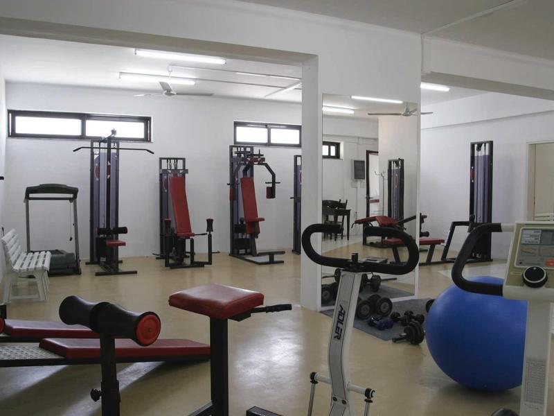 Palestra luminosa con varie attrezzature per l'allenamento e specchi alle pareti.