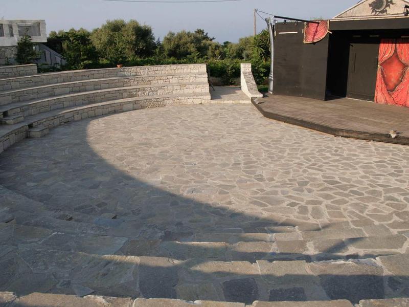 Anfiteatro all'aperto con panche in pietra e palco sotto cielo sereno.