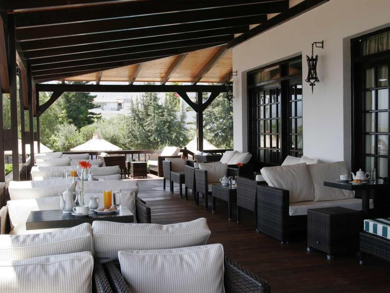 Terrazza coperta con comodi posti a sedere e tavoli in un giardino dell'hotel.