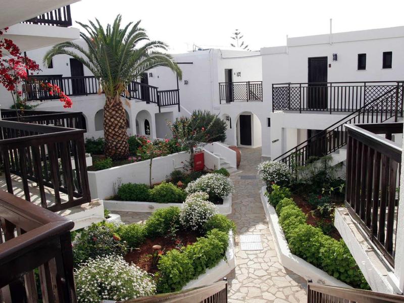 Cortile di un complesso di edifici bianchi con vialetto lastricato e piante decorative.