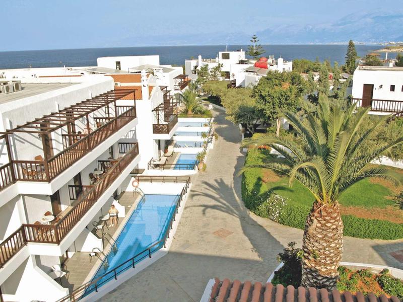Complesso alberghiero con piscina, palme e vista sul mare in una giornata di sole.