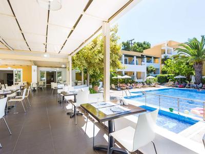 Moderní venkovní prostor hotelu s posezením vedle bazénu za denního světla