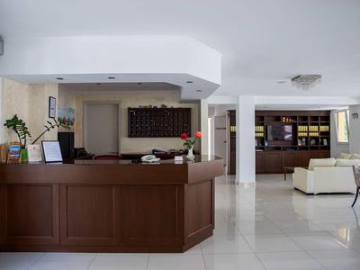 Réception d'hôtel élégante avec bois foncé, décor blanc et sol clair.