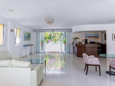 Réception lumineuse avec meubles blancs et entrée ouverte vers l'extérieur dans un hôtel.