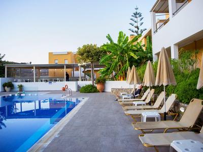 Moderní prostor u bazénu s lehátky a slunečníky vedle hotelové budovy.