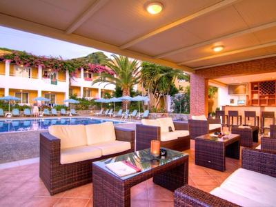 Coin salon confortable avec mobilier rembourré près de la piscine d'un hôtel au coucher du soleil.