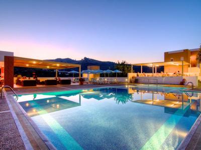 Moderní střešní terasa s osvětleným bazénem a posezením při západu slunce