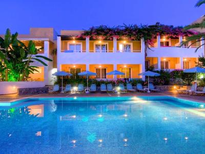 Hôtel moderne avec piscine éclairée et balcons au crépuscule.