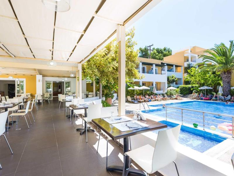 Terrasse d'hôtel avec chaises et tables à côté d'une piscine dans un cadre ensoleillé.