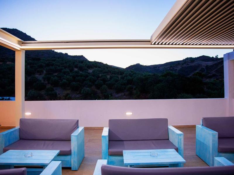 Terrasse moderne avec canapés et vue sur la montagne au coucher du soleil.