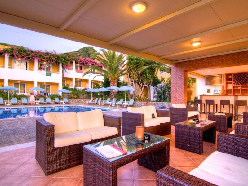 Coin salon confortable avec mobilier rembourré près de la piscine d'un hôtel au coucher du soleil.