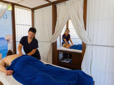 Woman receiving a massage in a bright room with white curtains and a mirror.