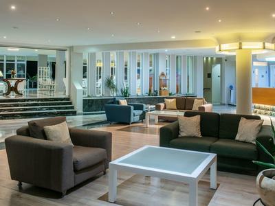 Modern eingerichtete Hotel-Lounge mit Sofas, Sesseln und einem weißen Tisch.