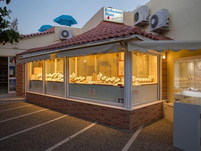 Illuminated jewelry store with large glass front and parking spaces in front at dusk.