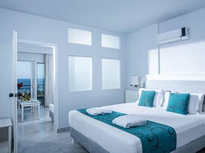 Bright modern hotel room with large bed and sea view.