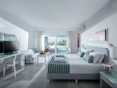 Modern hotel room with double bed and sea view from the balcony.