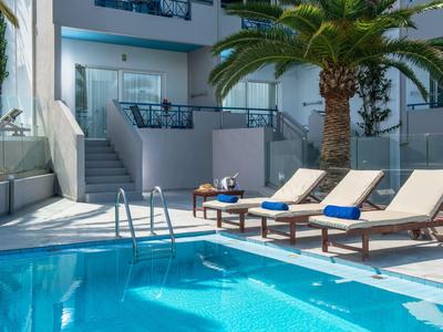 Hotel pool with four lounge chairs and towels next to palm trees in daylight.