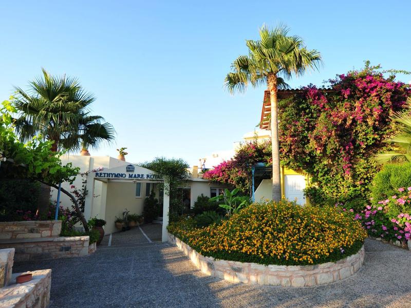Courtyard with palm trees, blooming plants, and a paved path in a hotel area.
