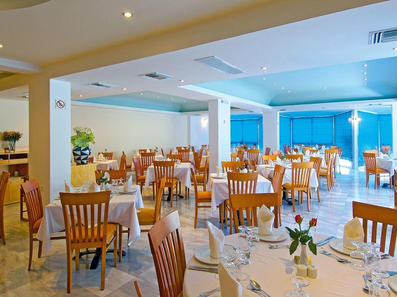 Bright hotel restaurant with set tables and wooden chairs.