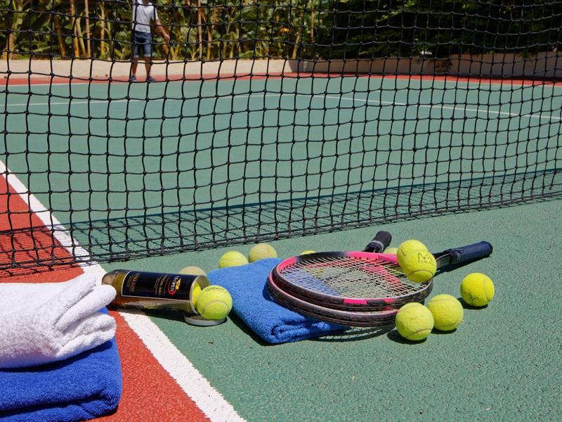 Tennis court with racket, tennis balls, and towels near the net.