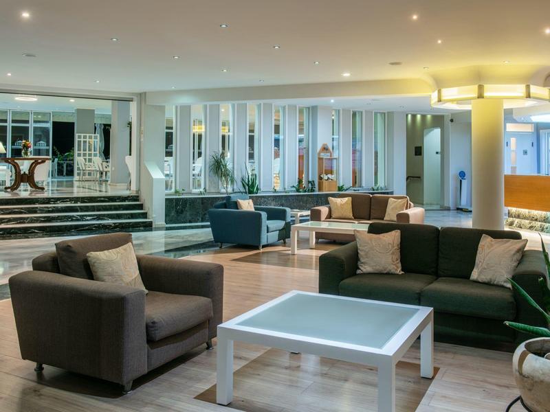 Modernly furnished hotel lounge with sofas, armchairs, and a white table.