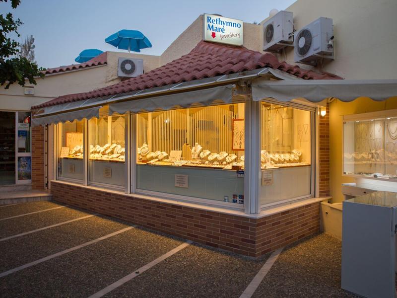 Illuminated jewelry store with large glass front and parking spaces in front at dusk.