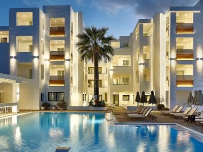 Hotel moderno con piscina esterna illuminata e palme al tramonto