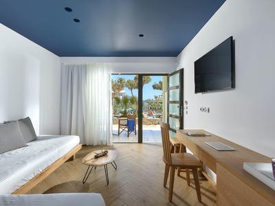 Elegante camera d'hotel con terrazza, mobili in legno e vista su palme.