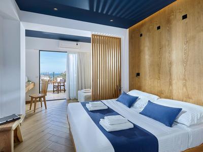 Camera d'hotel moderna con letto matrimoniale, parete in legno e balcone con vista sul mare.