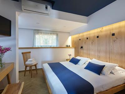 Camera d'hotel moderna con letto grande, pannelli in legno e luce calda.