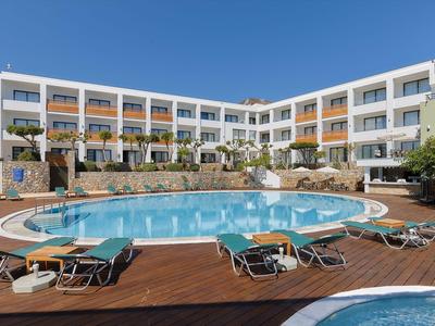 Hotel con piscina rotonda e sdraio su terrazza in legno sotto cielo sereno