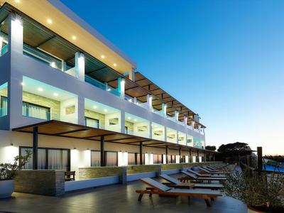 Area piscina moderna dell'hotel con lettini e ringhiere in vetro sotto un cielo limpido.
