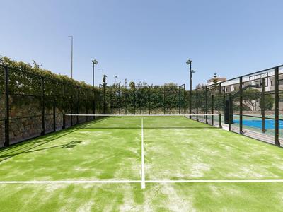 Campo da padel all'aperto con erba sintetica verde e rete protettiva in giornata soleggiata