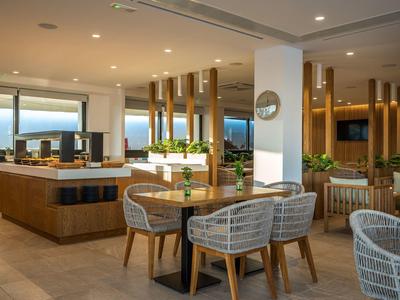 Interno ristorante moderno e luminoso con mobili in legno e ampie finestre panoramiche con vista sul mare.