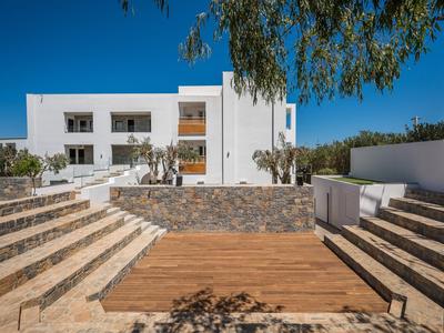 Complesso alberghiero bianco moderno con scale e piattaforma in legno sotto un cielo blu.