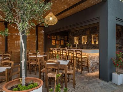 Bar all'aperto accogliente con sedie e tavoli in legno e luci sospese circondata da piante.