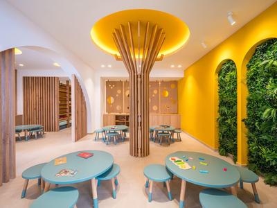 Sala giochi moderna e colorata con tavoli, sedute e pareti vivacemente decorate.