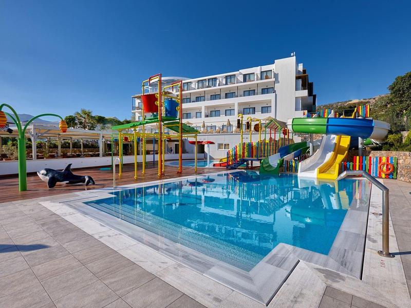 Piscina di un hotel moderno con scivoli d'acqua e ombrelloni sotto un cielo limpido.