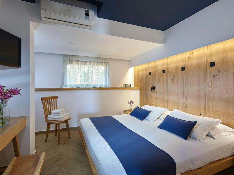 Camera d'hotel moderna con letto grande, pannelli in legno e luce calda.