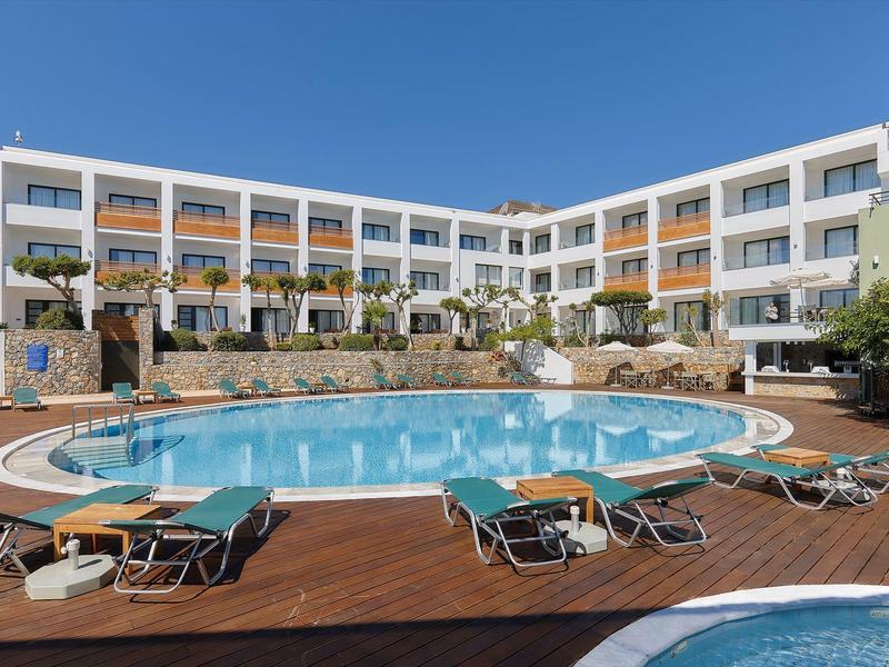 Piscina rotonda dell'hotel con lettini e edificio su più piani sotto un cielo sereno.