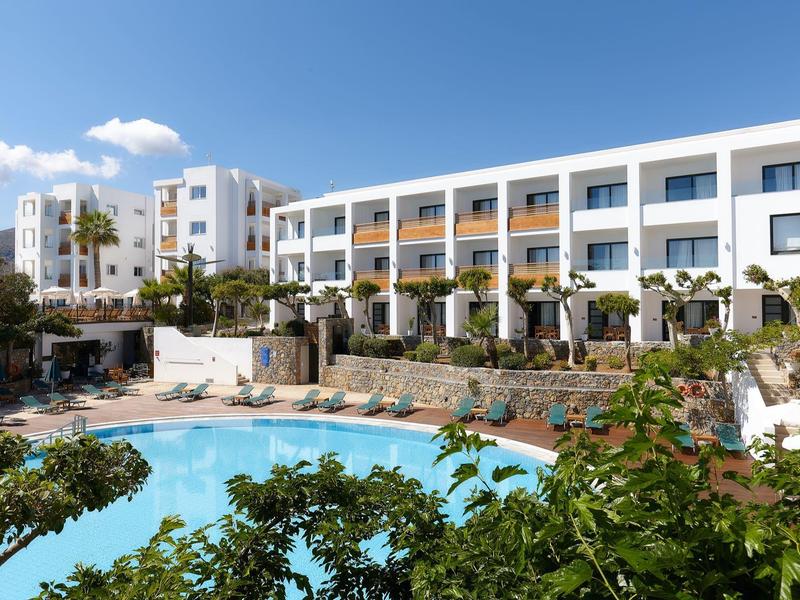 Hotel moderno con piscina, lettini e palme sotto un cielo azzurro.