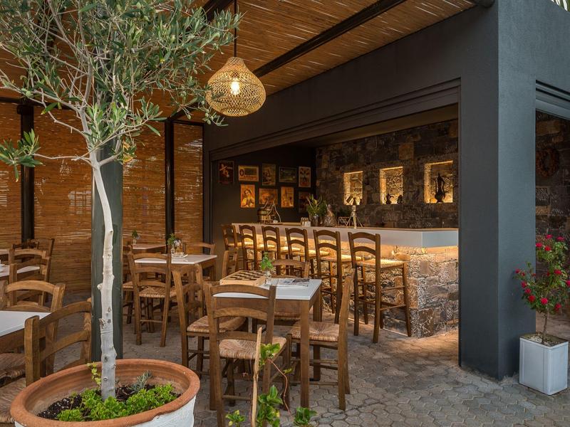 Bar dell'hotel accogliente con sedie di legno, tavoli e illuminazione calda nel cortile.