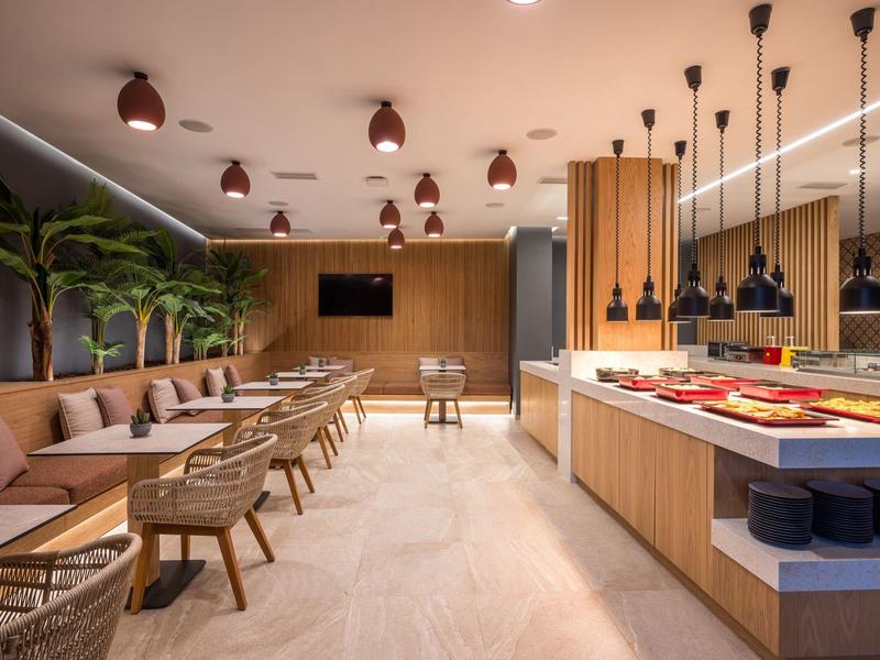 Sala colazione moderna con mobili in legno, posti a sedere e area buffet.