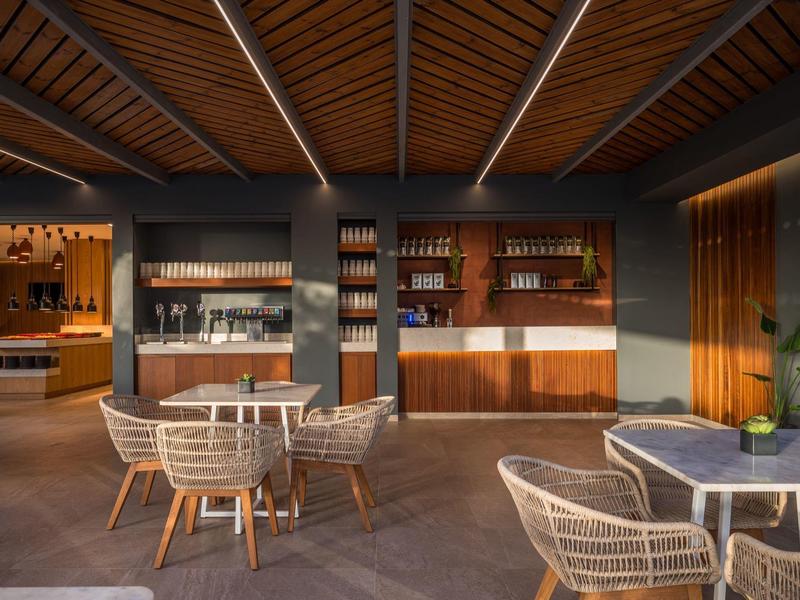 Area esterna moderna di un hotel con sedie e tavoli eleganti al tramonto.